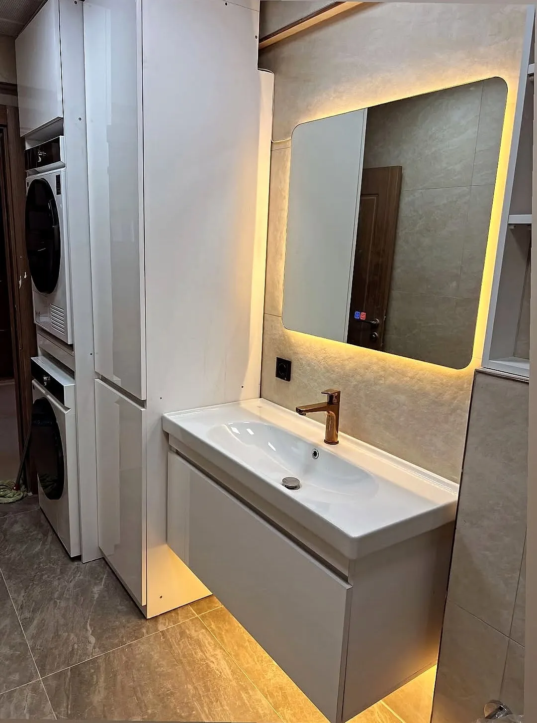 Lavabo dolabı; solda çamaşır ve kurutma makinelerinin üst üste durduğu boy dolap